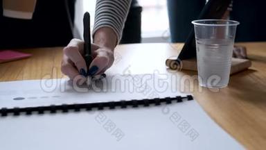 一个女人的手在报纸上指指点点地写着办公室里的一个新项目。